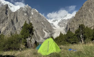 Alpine meadows camping Pakistan with tents at Fairy Meadows base camp facing Nanga Parbat glacier and peaks